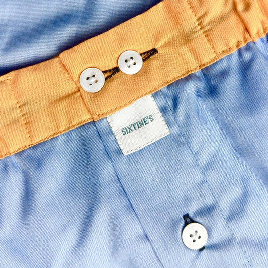 Close-up of a blue shirt with yellow collar and buttons, featuring the 'Sixtine's' brand label.